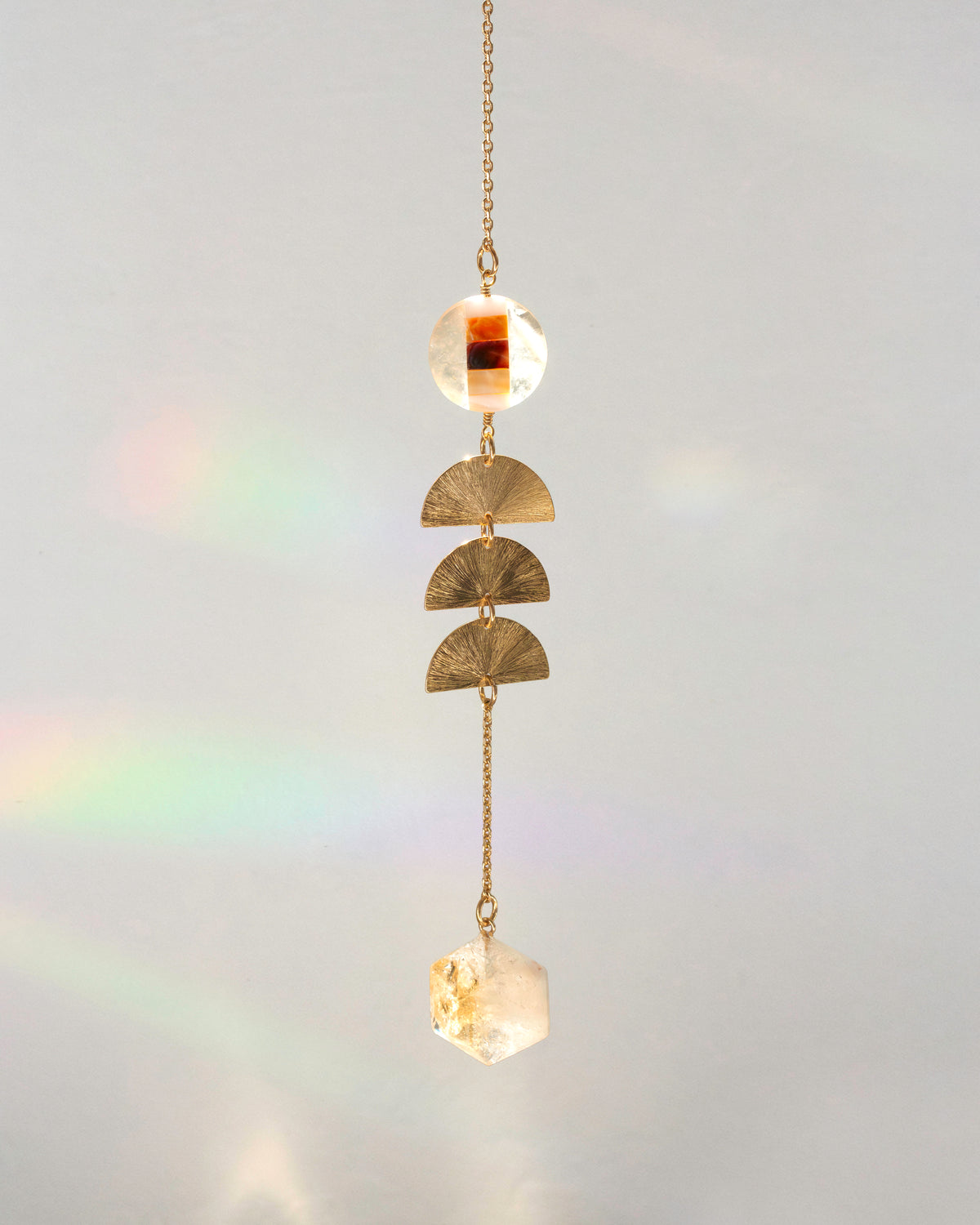 A gold-toned hanging ornament with three textured gold semicircle discs, and a citrine faceted crystal pendant.