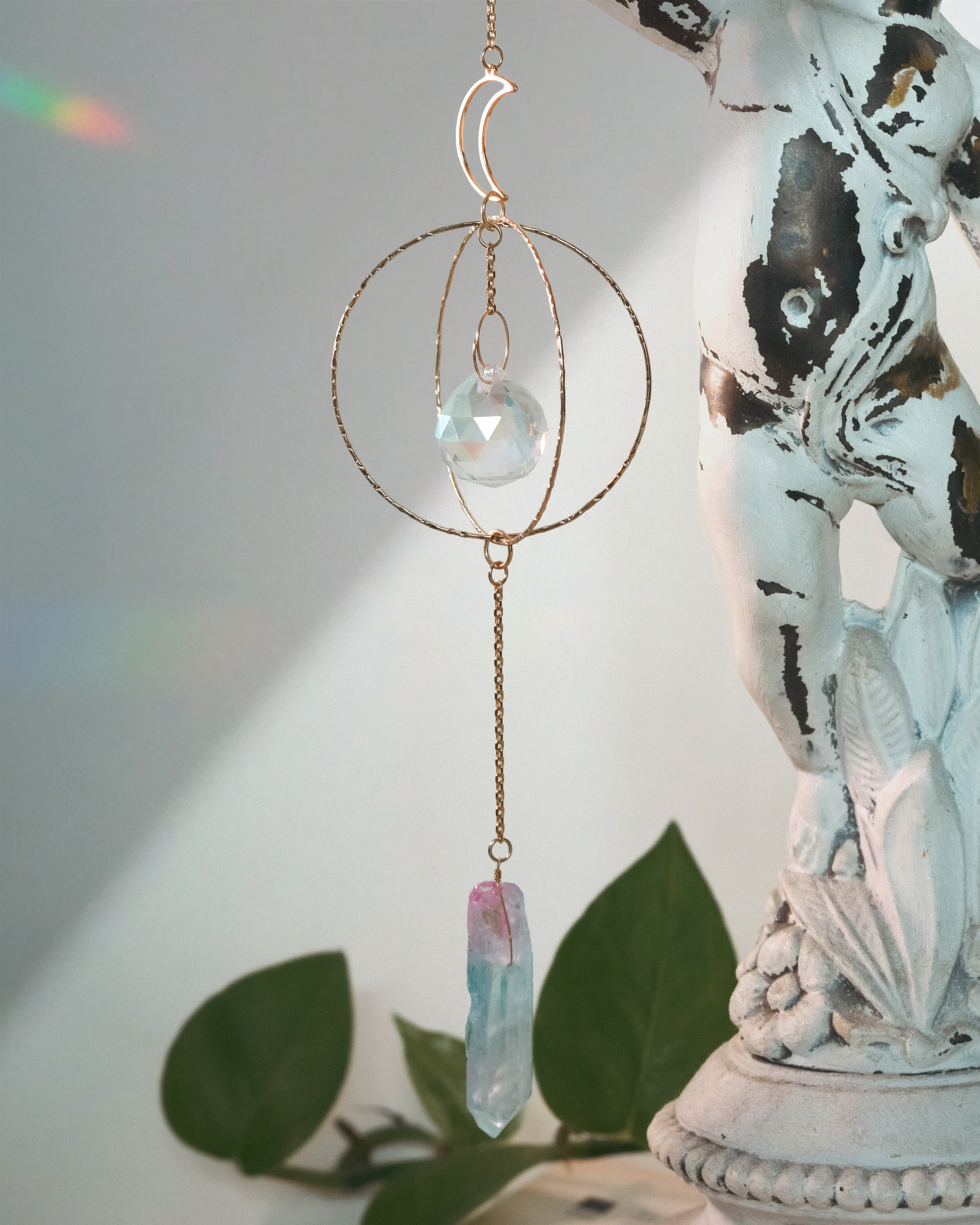 Decorative hanging crystal with a statue and plant in the background