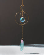Decorative hanging crystal with gold chain and blue crystal on a dark background