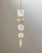 Decorative hanging pendant with stones and gold accents on a gray background