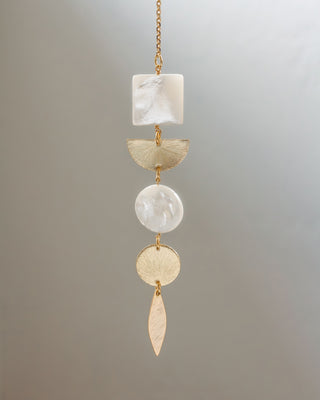 Decorative hanging pendant with stones and gold accents on a gray background
