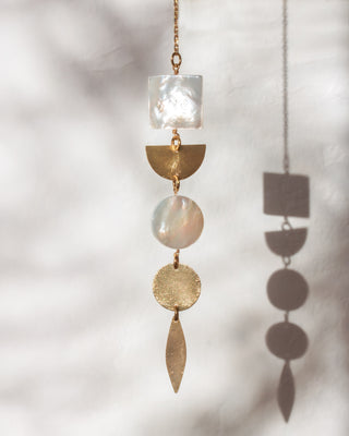 Decorative hanging with gold and shell elements on a light background