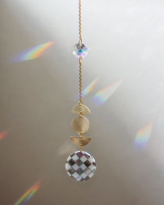 Decorative hanging chain with circular beads and a checkered pattern on a neutral background
