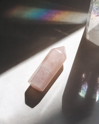 Pink crystal on a reflective surface with rainbow light flash