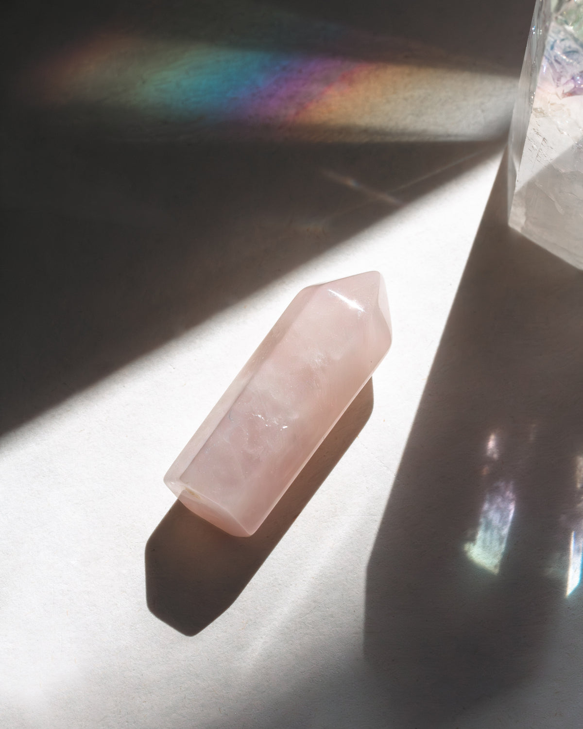 Pink crystal on a reflective surface with rainbow light flash