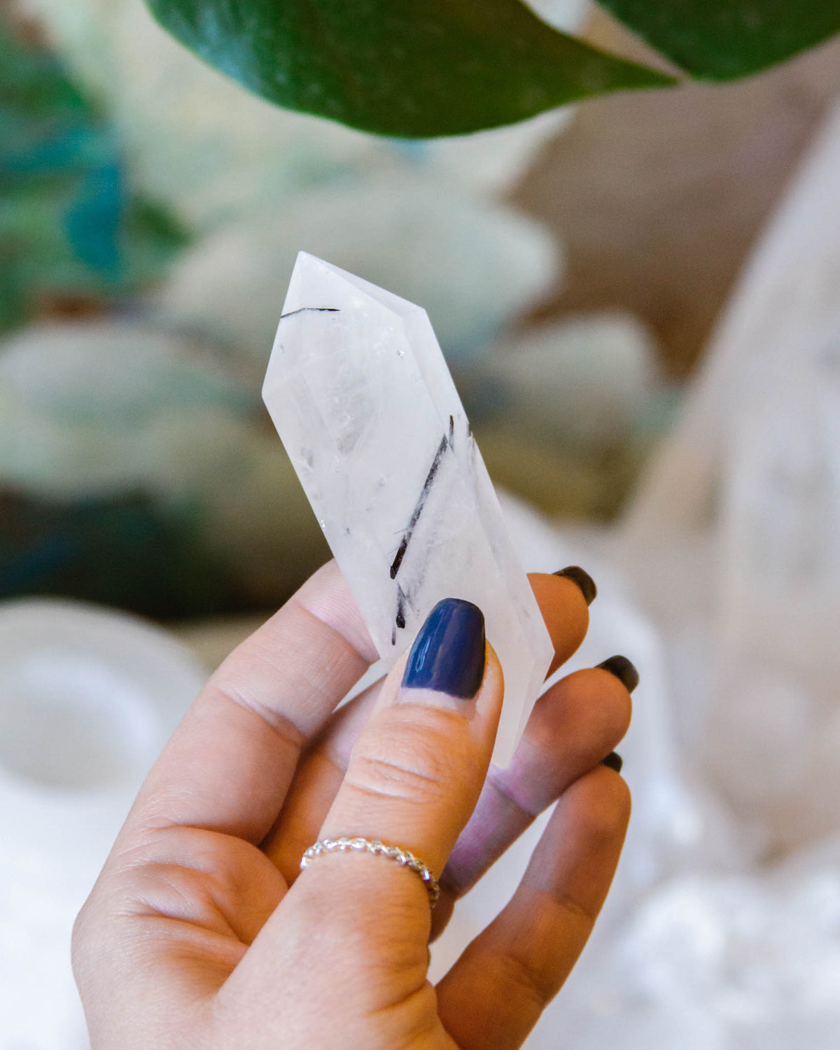 Hand holding a Tourmalinated Quartz crystal point.