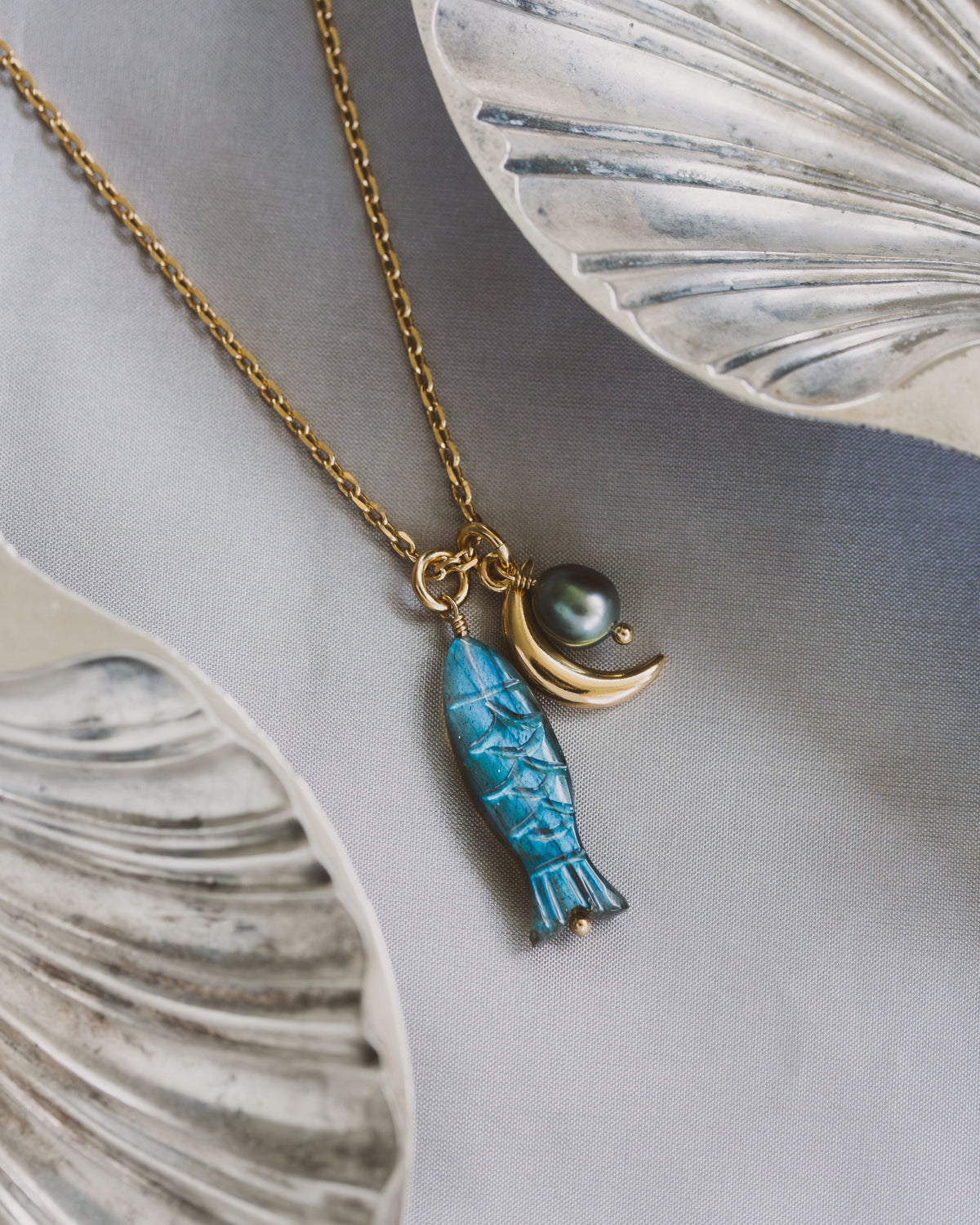 Necklace with blue labradorite fish charm and freshwater pearl, and gold crescent moon charm