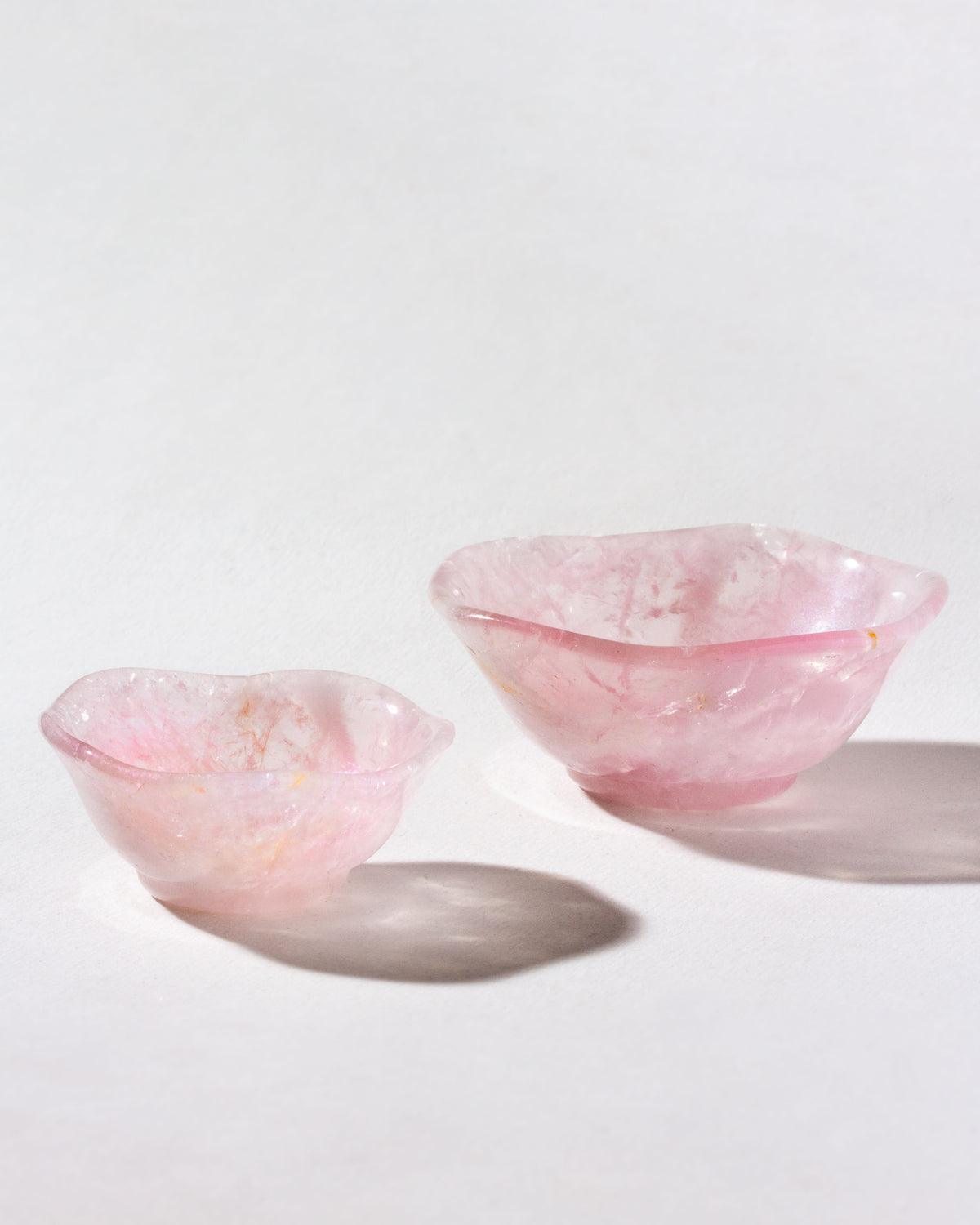 Two nested rose quartz bowls with a subtle wavy pattern