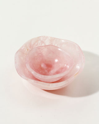 Two rose quartz nesting bowls on a neutral background, one small inside the other, with a subtle wavy pattern.