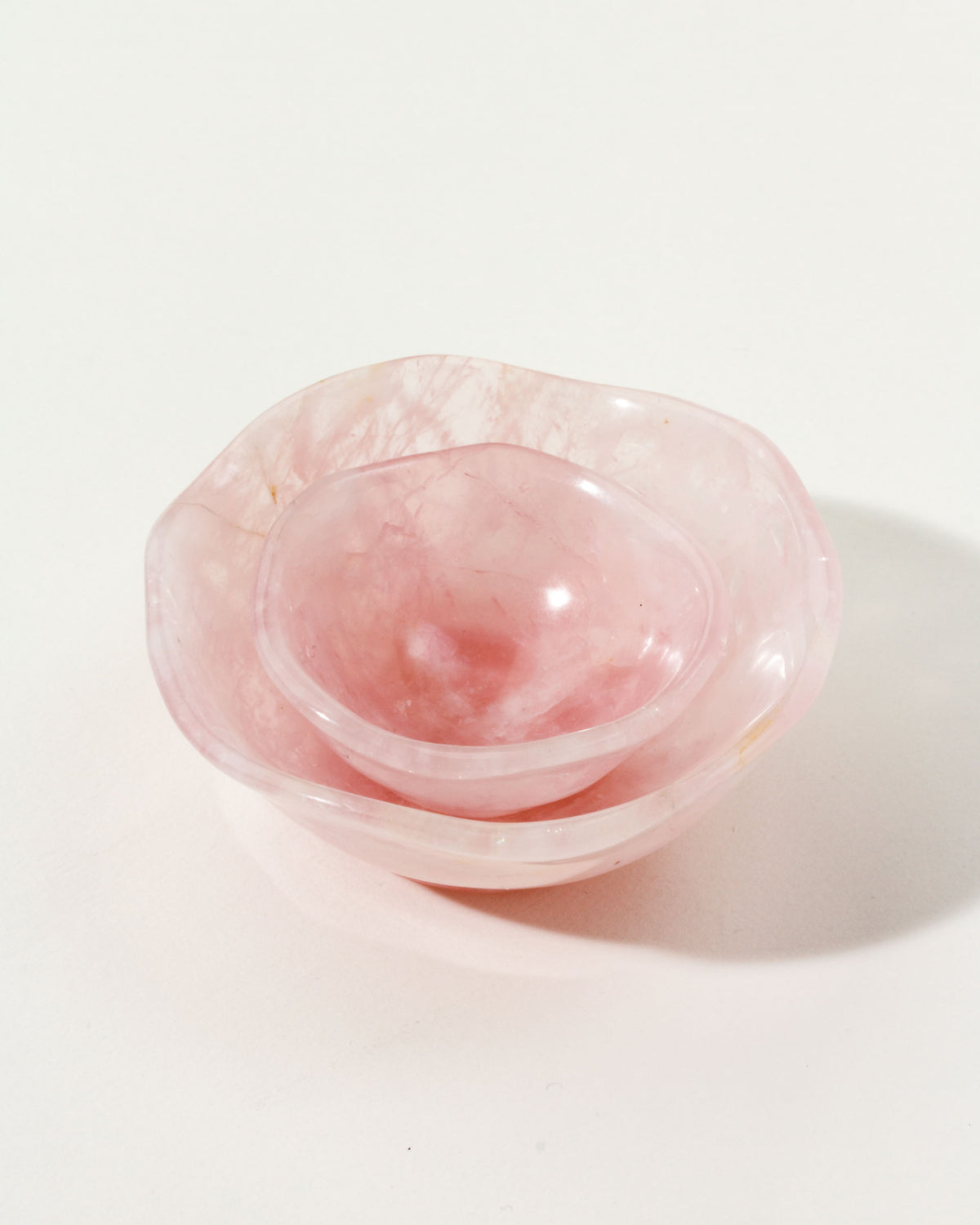 Two nested rose quartz bowls with a subtle wavy pattern