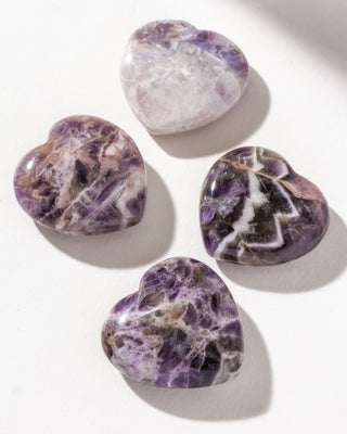 Four heart shaped chevron Amethyst gemstones on a white backgrounds.