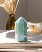 A green aventurine gemstone carved into a faceted tower shape, on a flat stable