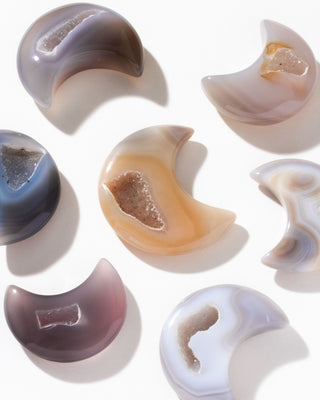 Various multicolored druzy agate crescent moon curios on arranged on a white background.