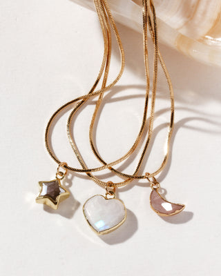 Moonstone, Coffee Moonstone, and peach moonstone Gold-colored snake chain necklaces with various charms including a heart, star, and crescent moon, displayed against a light background.