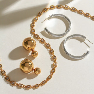Gold and silver minimal metal only essentials earrings and necklaces laying on a white table.