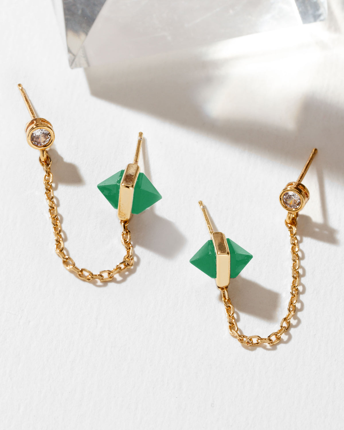 Gold crystal stud chain earrings with green dual-sided pyramid onyx gemstones on a white background
