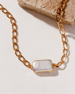 A minimalist collar chain necklace with a rectangular pearl centerpiece, suspended on a gold-colored chain.