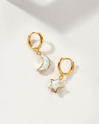 Pair of mismatched gold huggie hoop earrings with moonstone star and moon charms