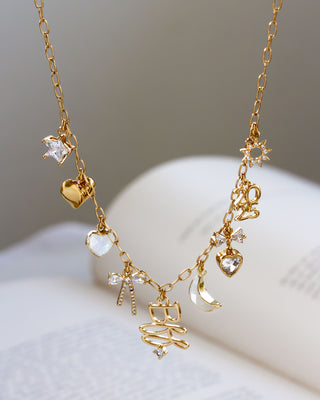 Gold necklace with various charms on a soft surface