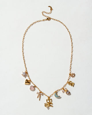Gold necklace with various charms on a light gray background