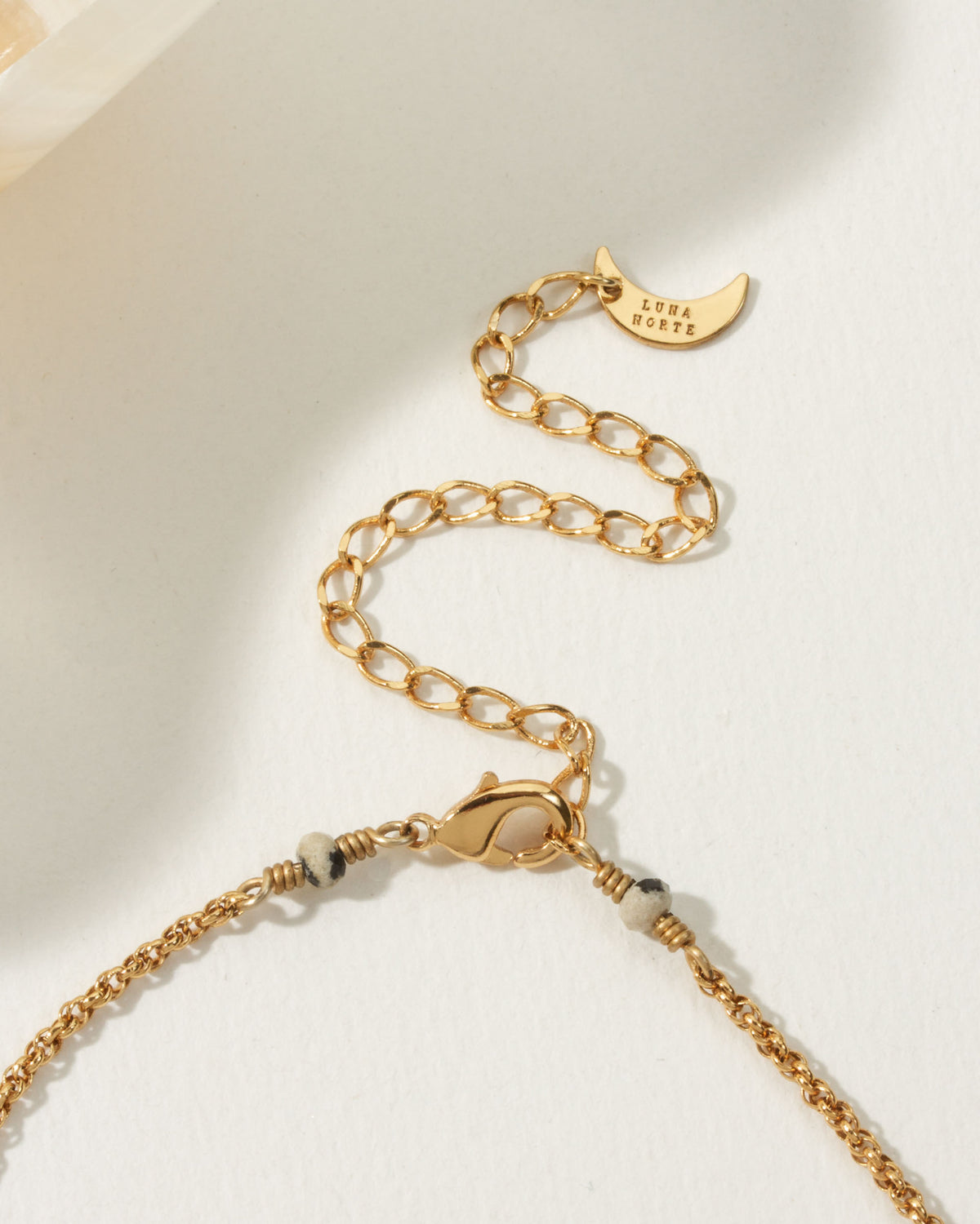 Close-up of the Spot On Medallion Necklace's gold chain, clasp, extender, and branded moon charm.