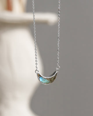 Silver necklace with a half-moon pendant on a blurred background