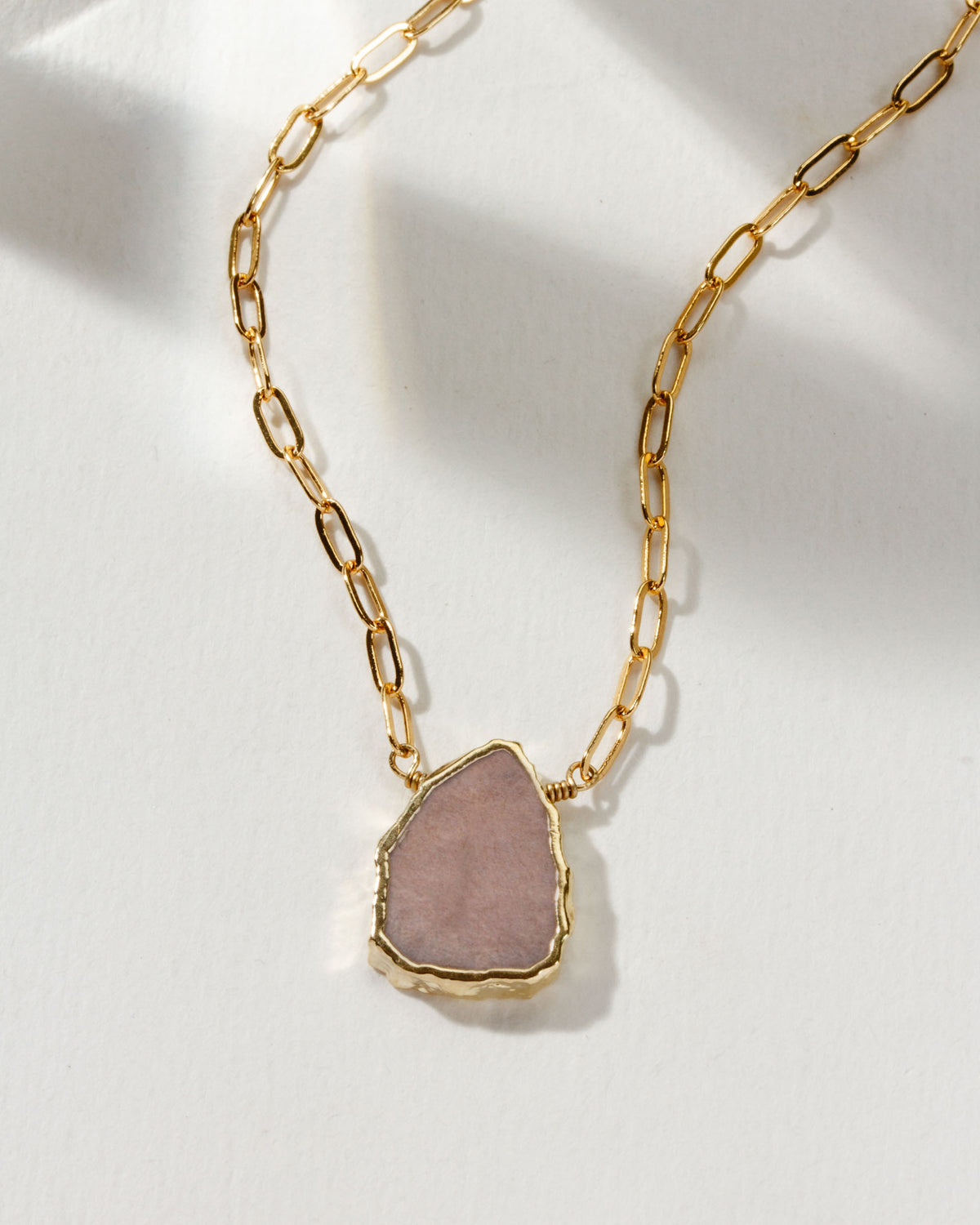 Gold chain necklace with a pink moonstone pendant.