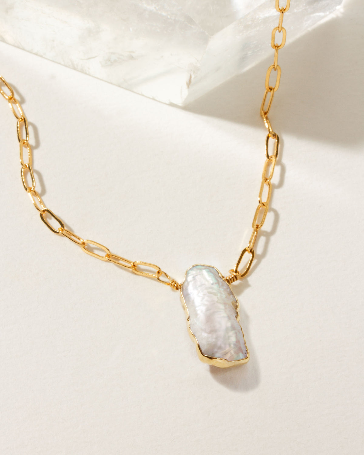 Elemental Force Necklace with a Freshwater Pearl pendant on a gold chain.