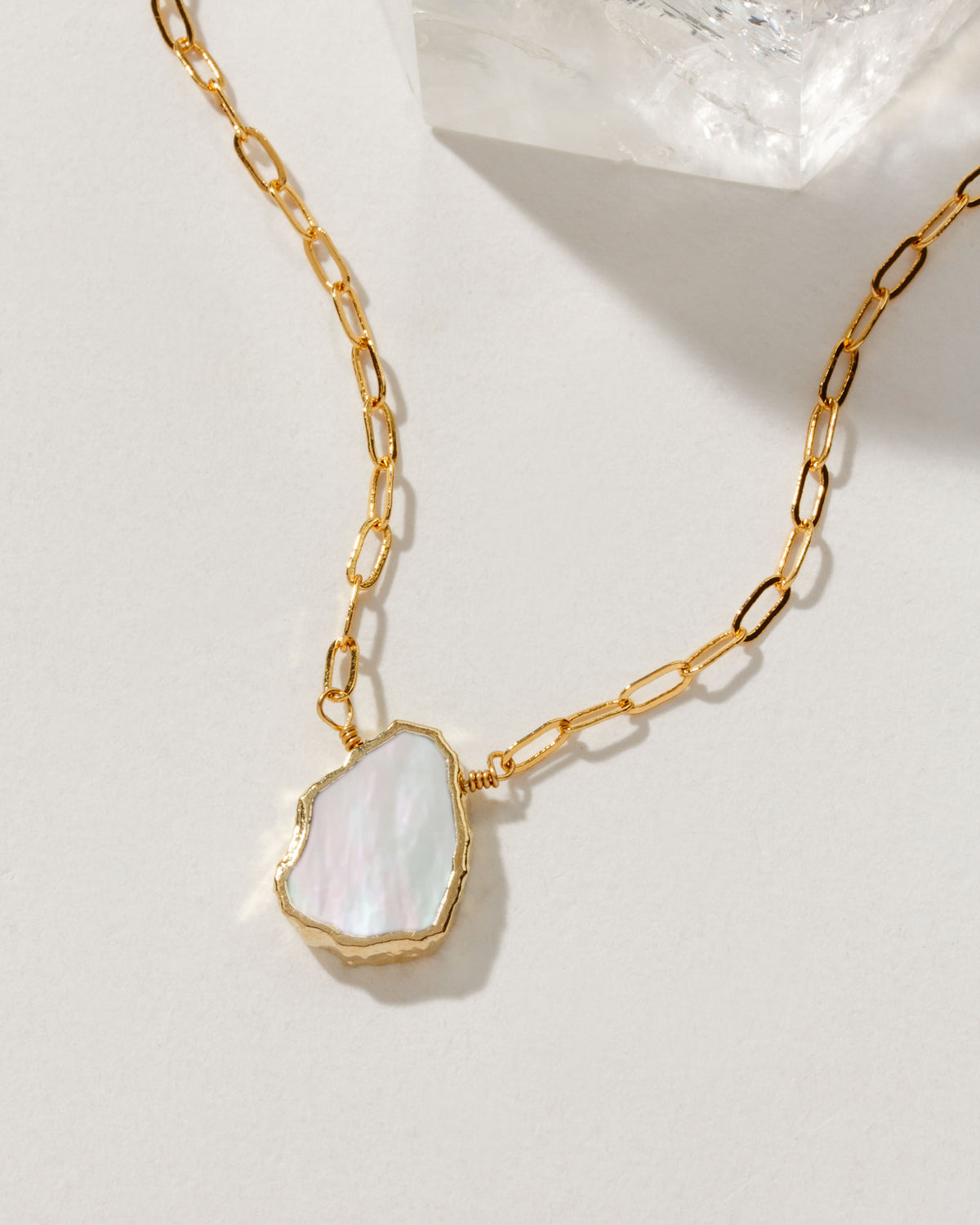 Gold chain necklace with a Mother of Pearl pendant.