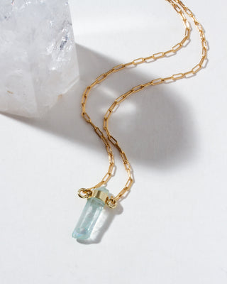 Gold necklace with a quartz gemstone pendant on a white background