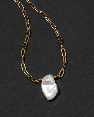 A gold paperclip chain necklace with a  white Keshi pearl pendant.
