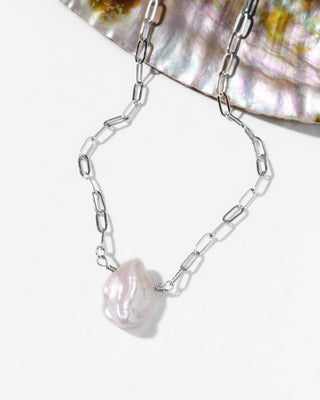 Silver chain necklace with a large pearl pendant on a white background