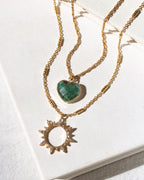 Two gold necklaces with emerald heart and sun-shaped pendants