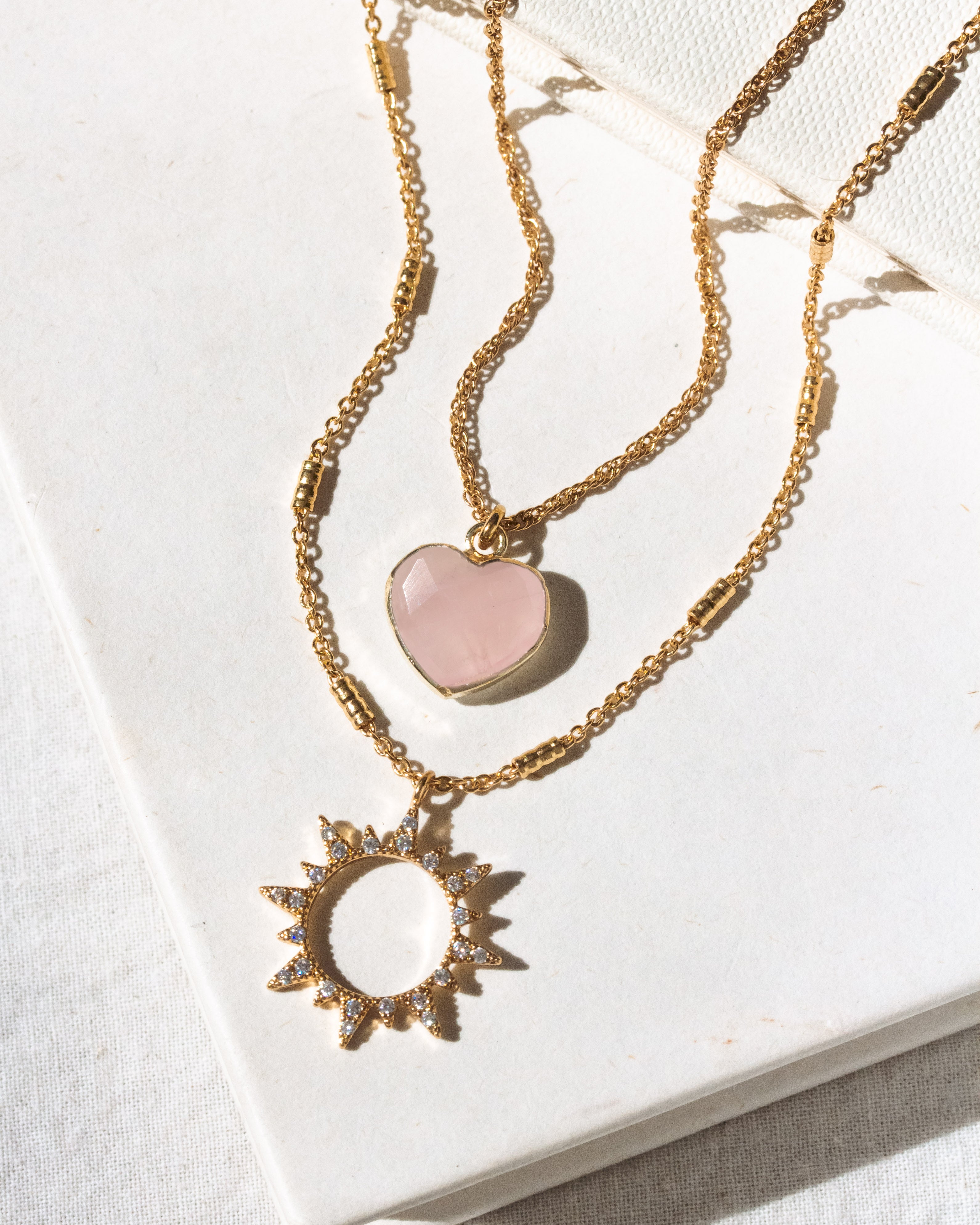 Gold necklace set with rose quartz heart and clear CZ sun charm pendant.