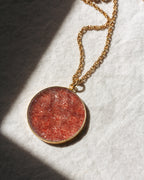 Necklace with a round red pendant on a textured white surface