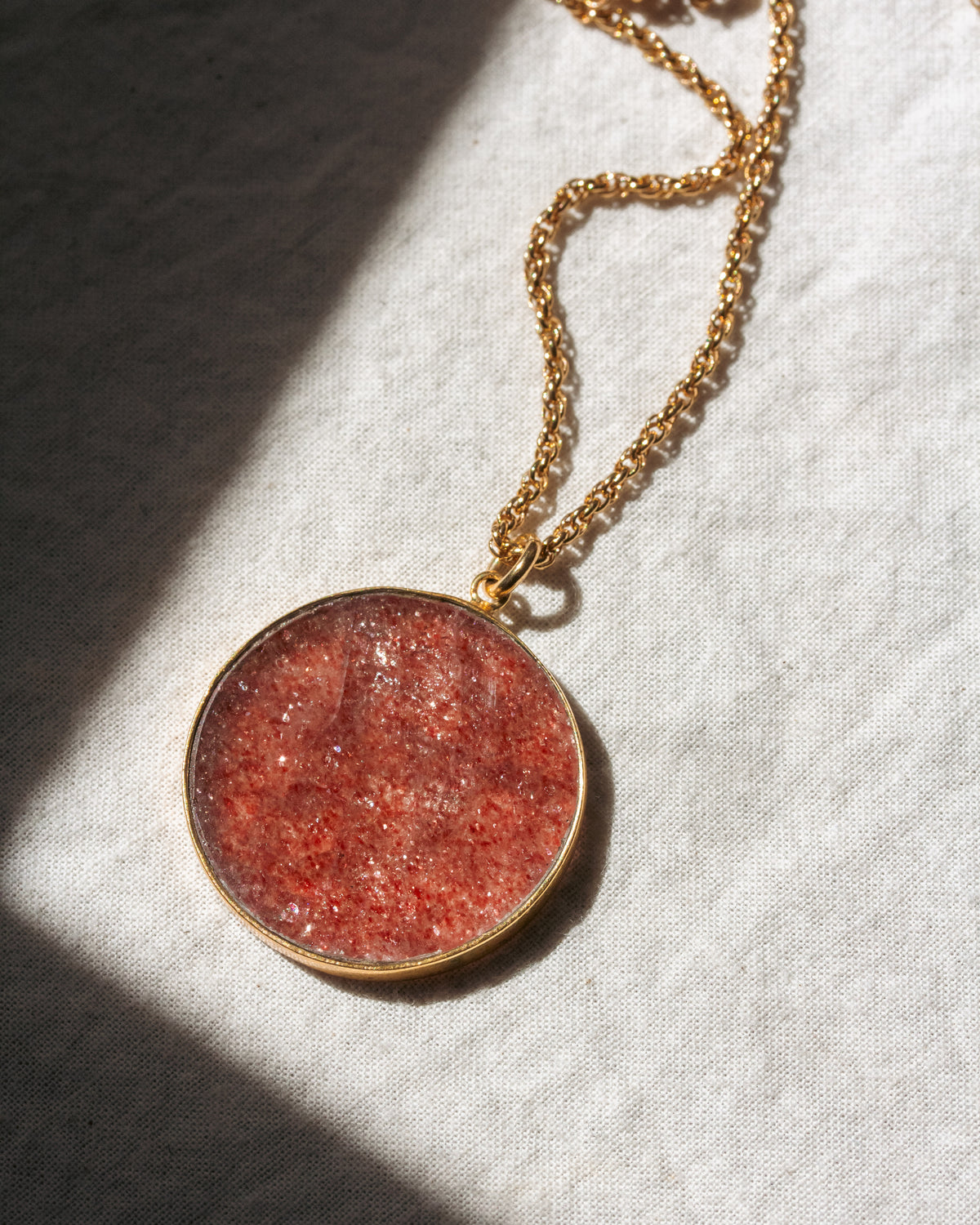 Necklace with a round red pendant on a textured white surface