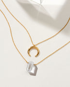 Gold necklaces featuring a crescent moon charm and a Clear Quartz point.
