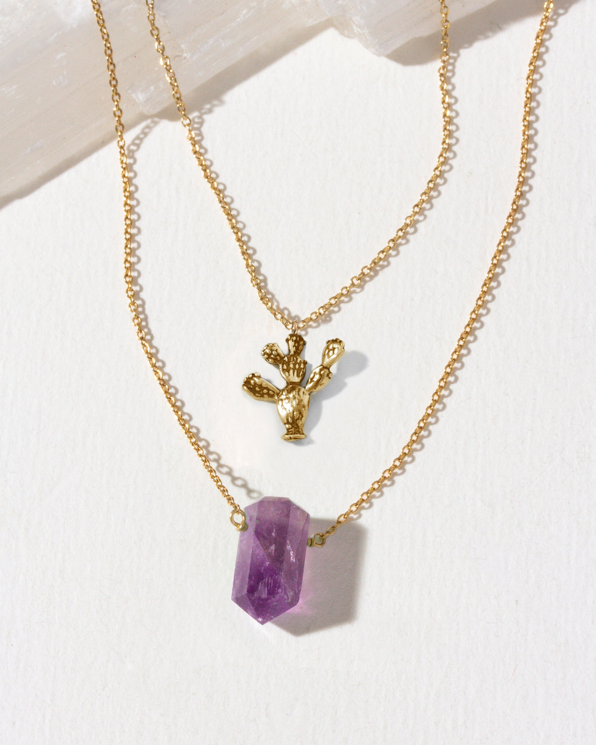Gold layering necklaces with a purple amethyst and gold prickly pear cactus pendants