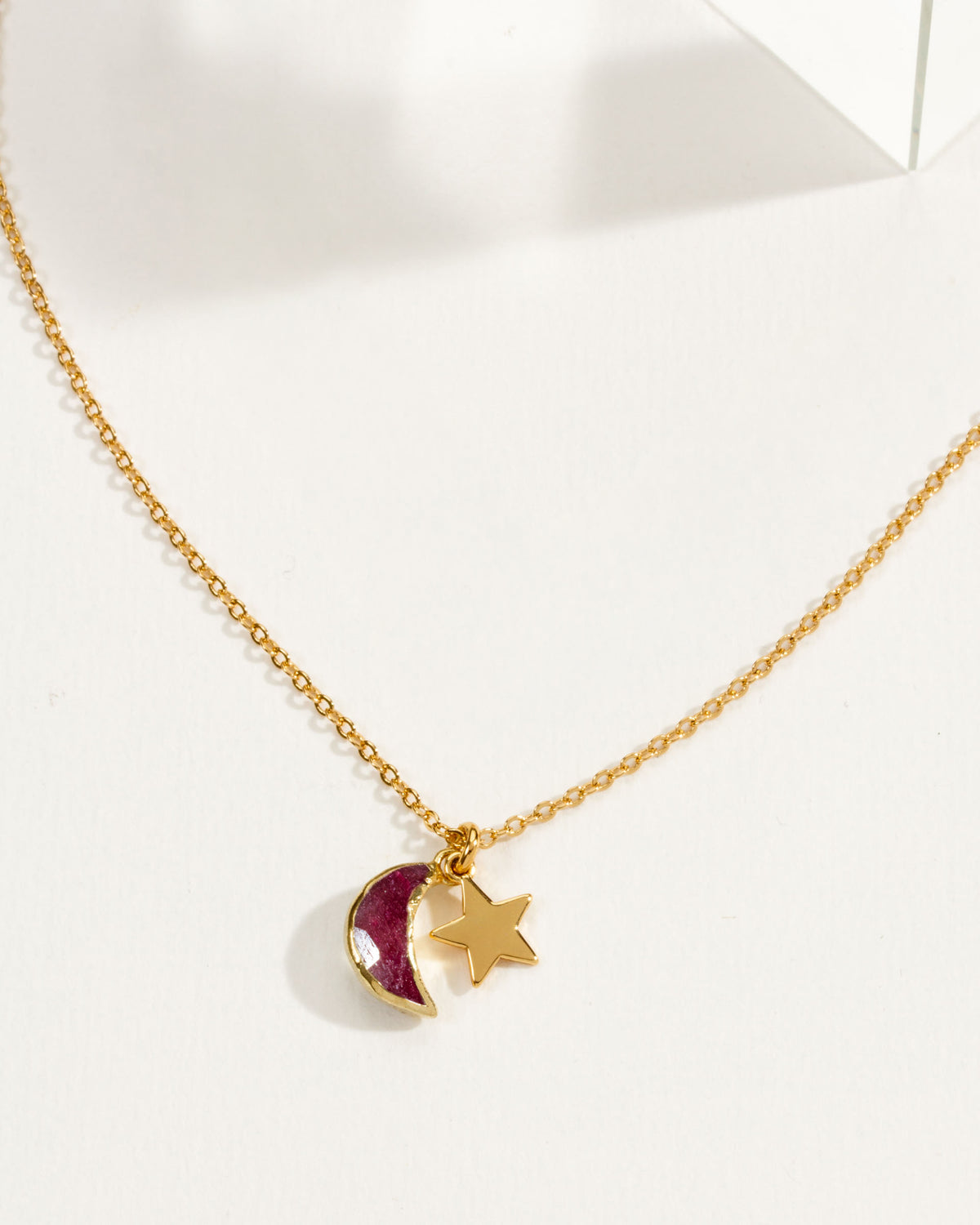 A gold chain necklace featuring a ruby crescent moon and star pendant.