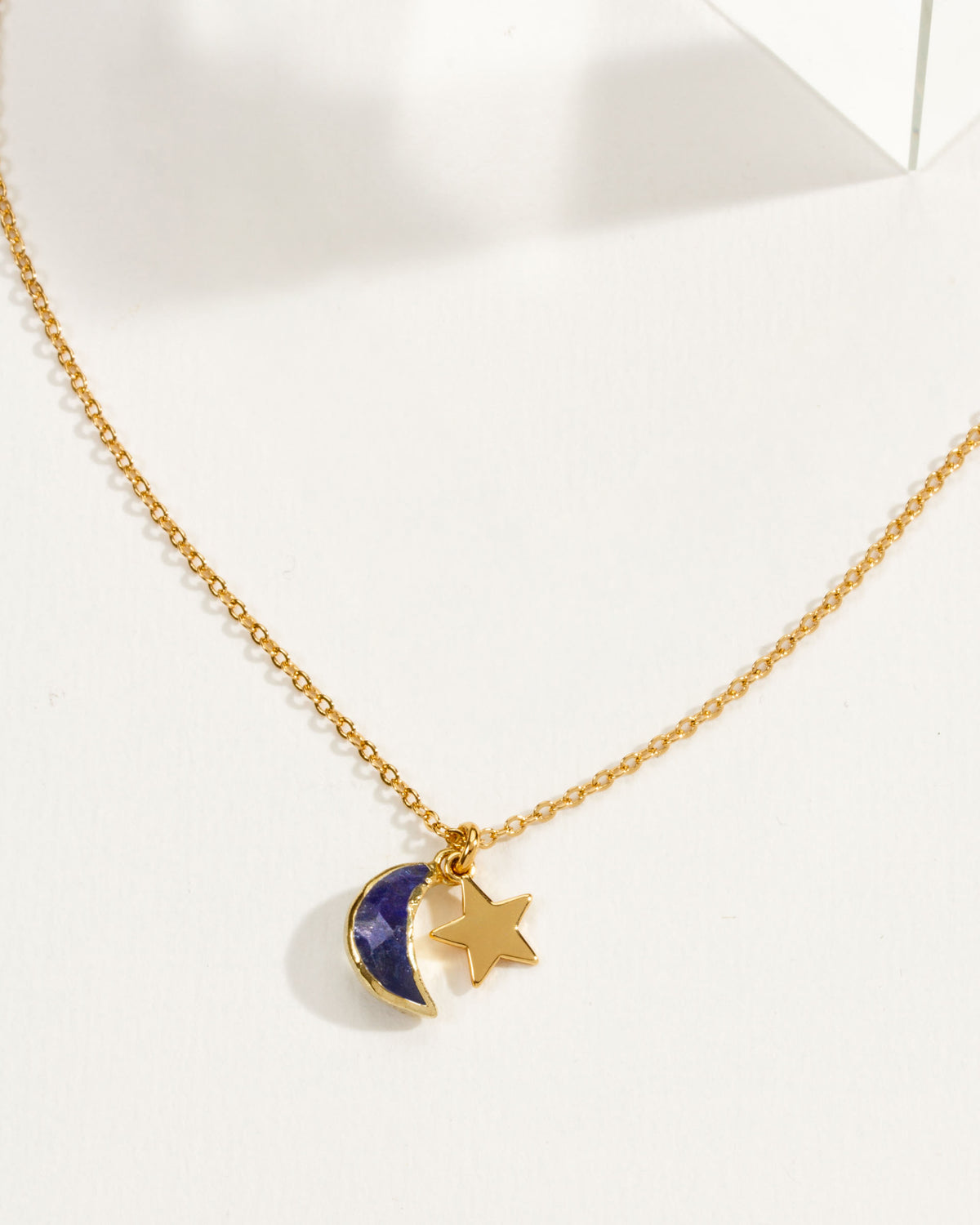 A gold chain necklace featuring a sapphire crescent moon and star pendant.