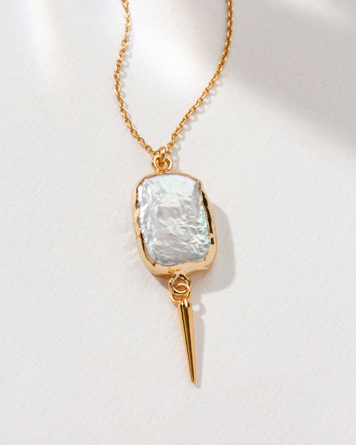 Gold chain necklace featuring a freshwater pearl pendant and quill accent.