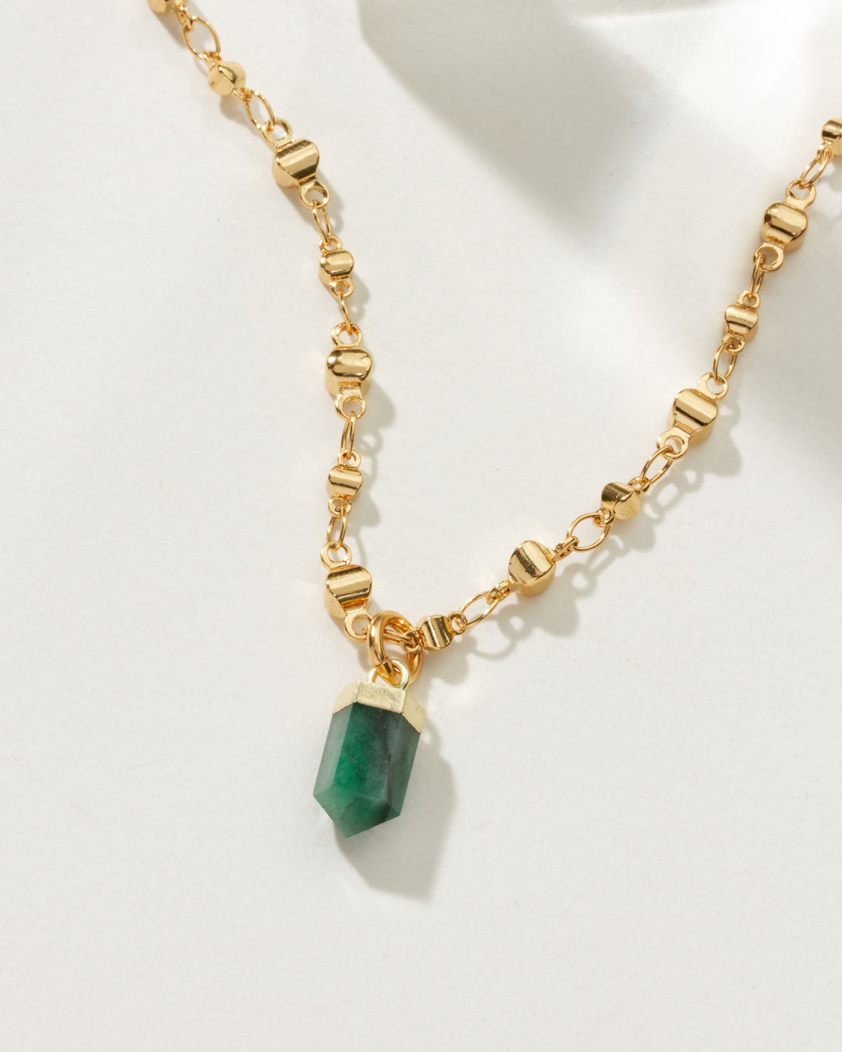 Gold necklace featuring an emerald point pendant.