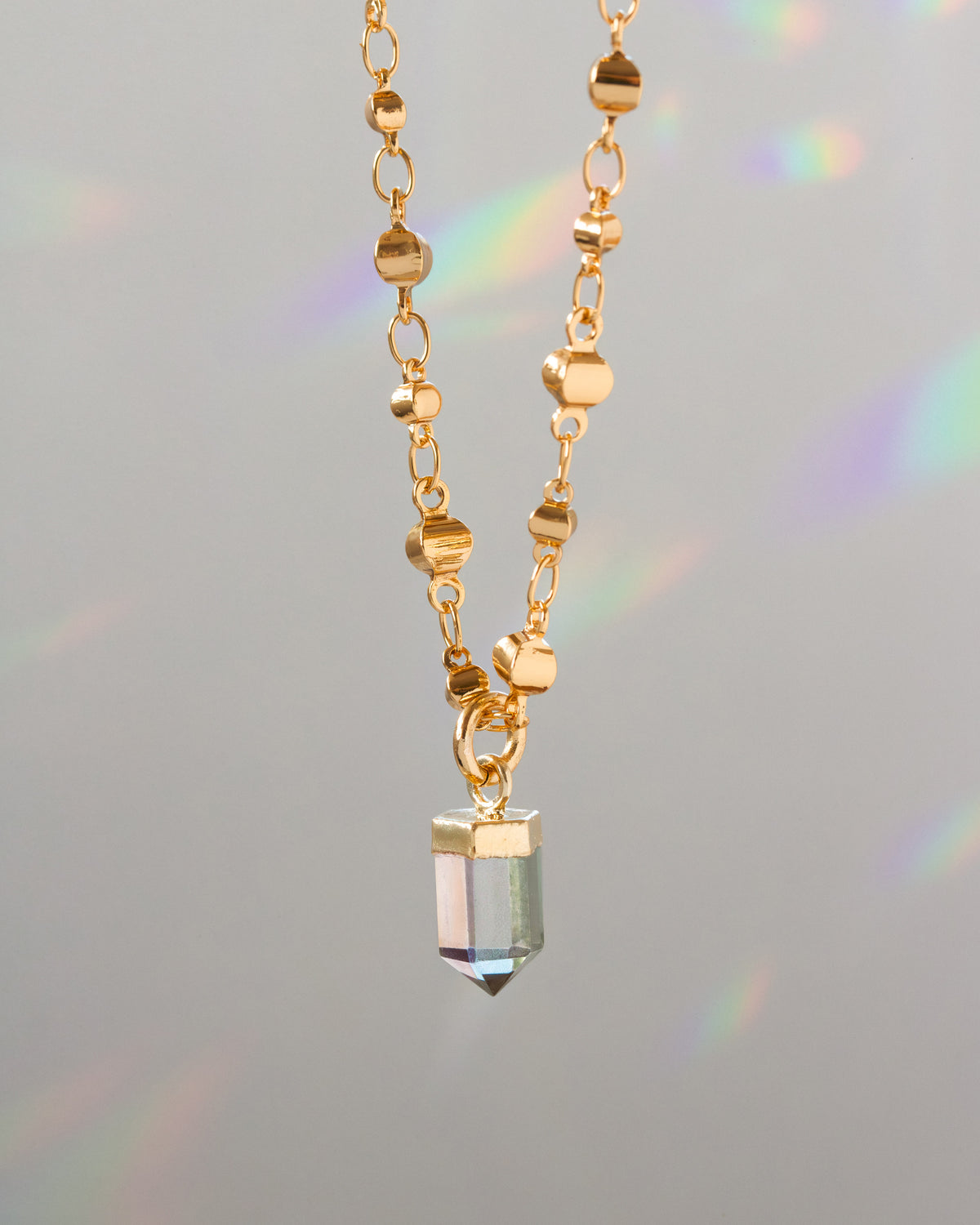 Gold necklace with a crystal pendant on a gray background