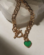 Gold chain necklace with toggle clasp and a green gemstone heart pendant.