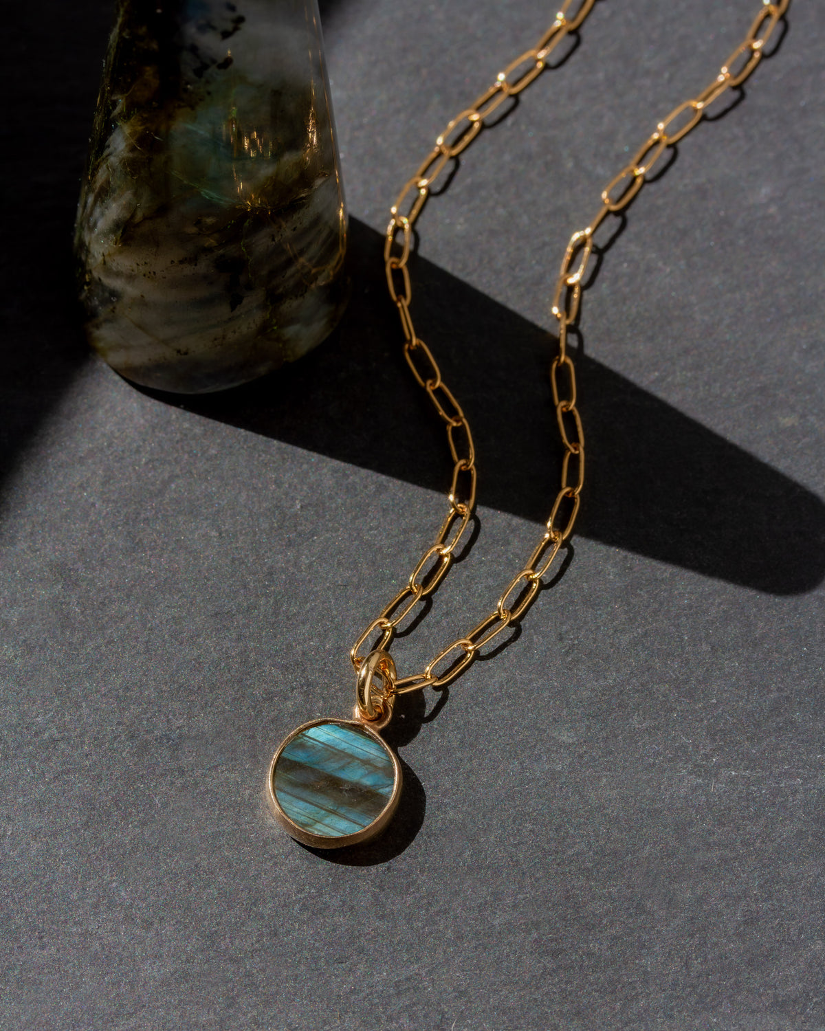 Gold necklace with a blue pendant on a dark surface