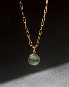 Gold necklace with alabradorite pendant on a dark background