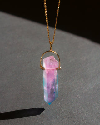 Necklace with a pink and blue crystal pendant on a dark surface