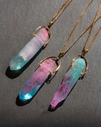 Three crystal necklaces with gold chains on a dark gray background