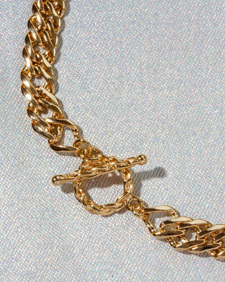Close-up of a chunky gold chain necklace with a toggle clasp.
