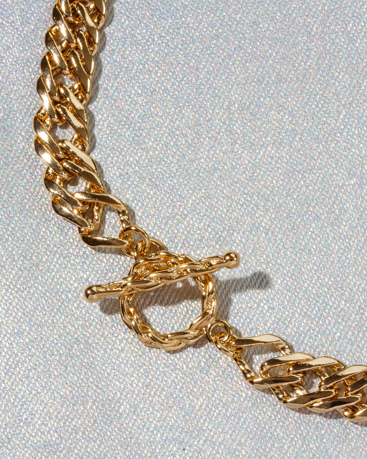 Close-up of a chunky gold chain necklace with a toggle clasp.